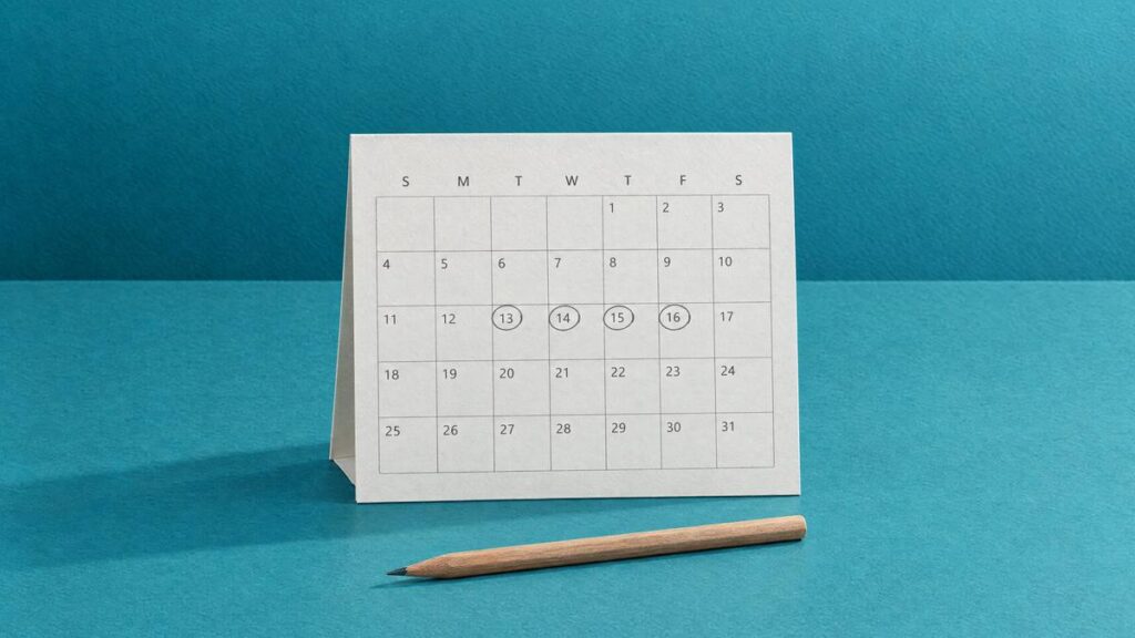 A desk calendar with four days circled in pencil, and a pencil lying in front of it